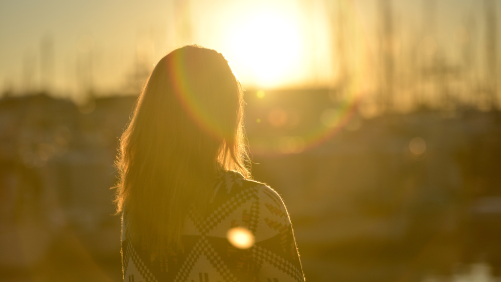Woman Standing Against Facing Sun with dawn, dust, evening, lens flare