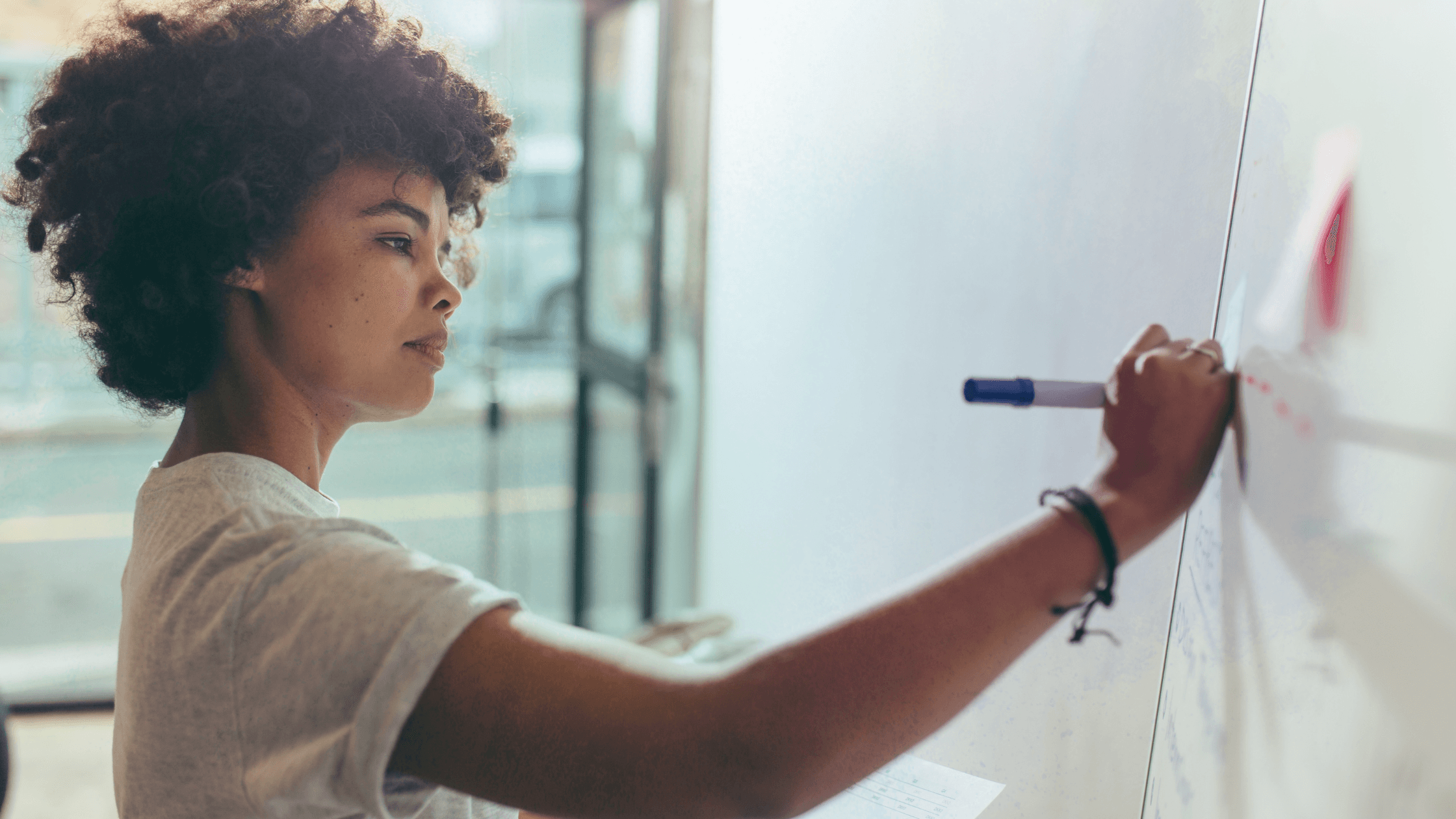 A thoughtful team member updates a whiteboard, symbolizing leadership through clarity, accountability, and quiet communication.